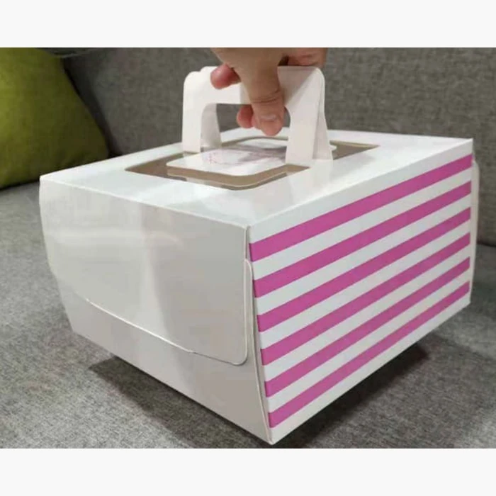 A white cake carrier box with pink stripes, carried by its handle