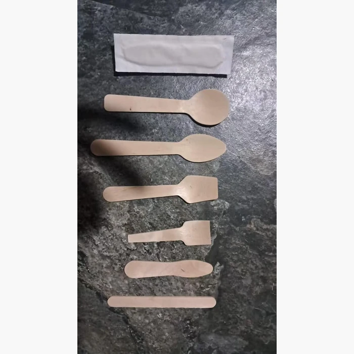 Six wooden cutlery shapes laid out on slate, with a paper sleeve